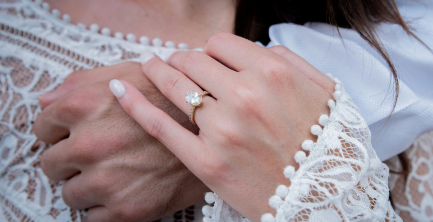 Womans hand with engagment ring holding mans hand